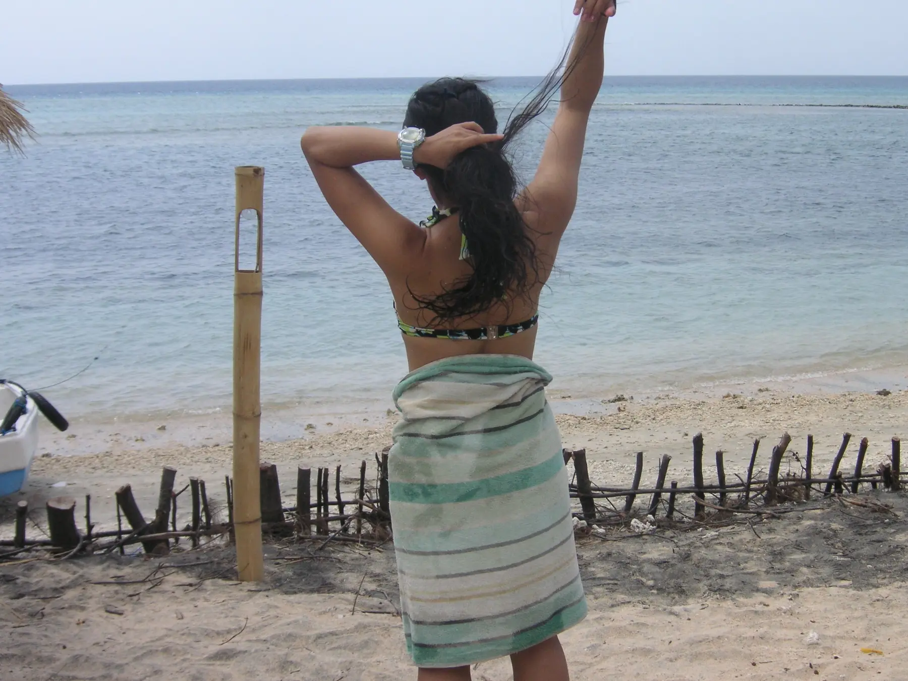 海を前に髪を結ぶ女性の後ろ姿